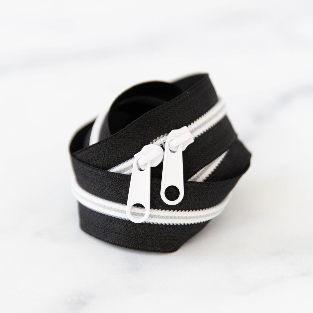 Black zipper with white zipper teeth on a white background