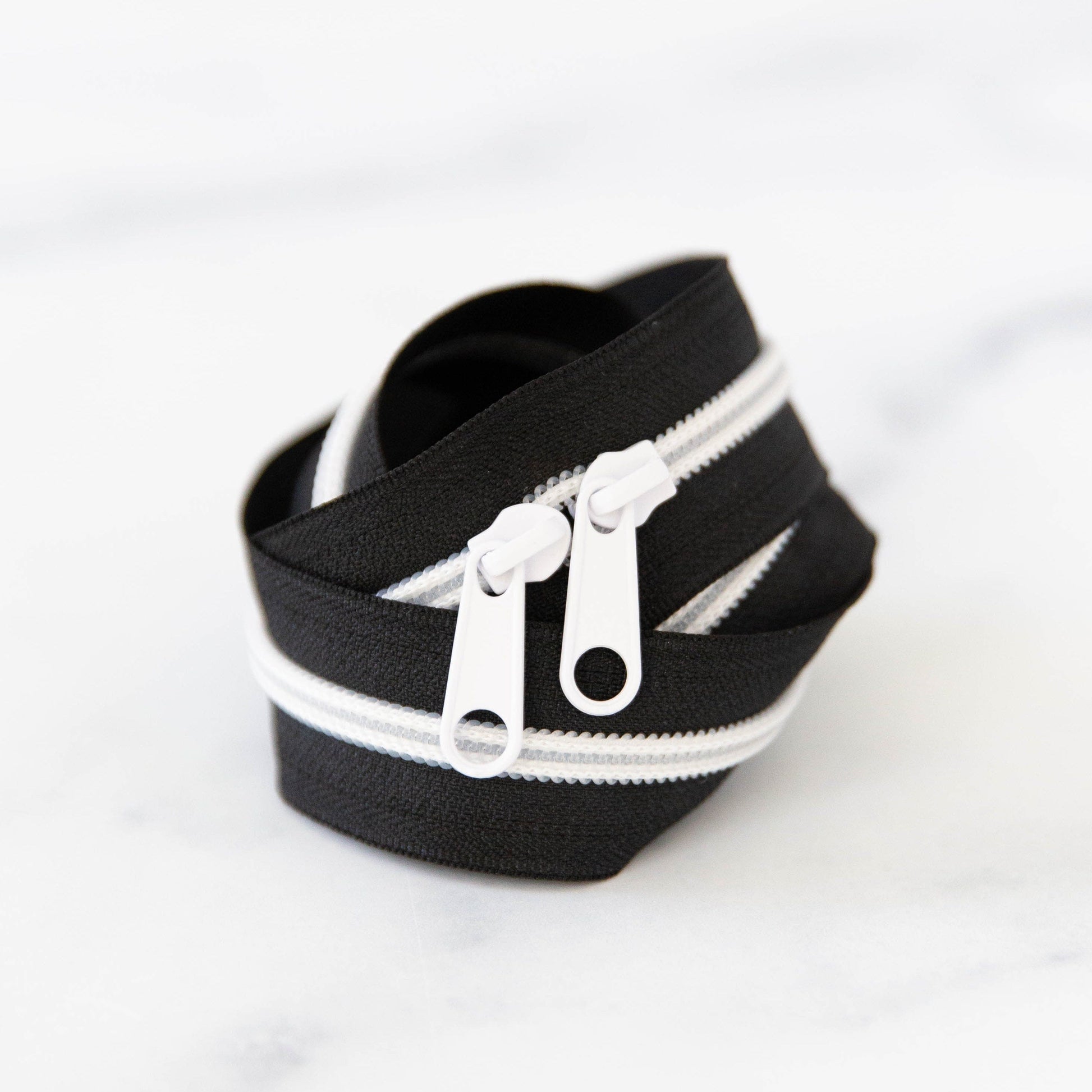 Black zipper with white zipper teeth on a white background
