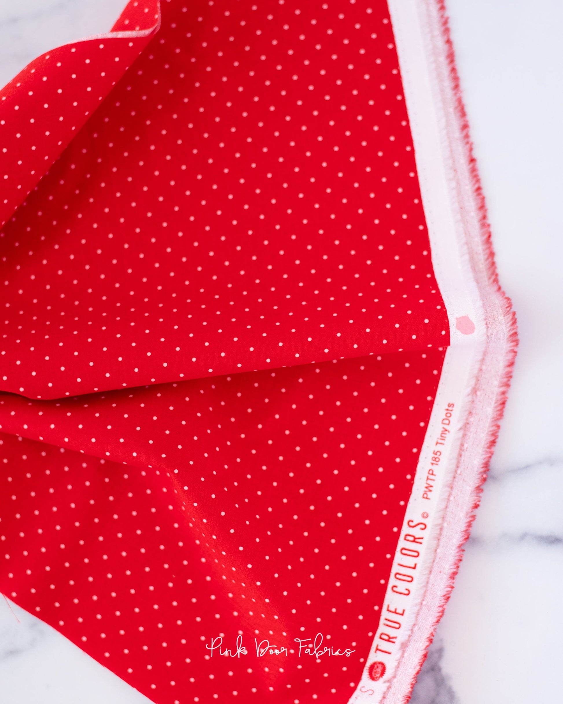 Cotton quilting fabric pattern called 'Tiny Dots in Watermelon'. Part of the 'True Colors' fabric collection. Designed by Tula Pink for fabric company Free Spirit Fabrics. SKU: PWTP185.WATERMELON. 44-45 inch width.