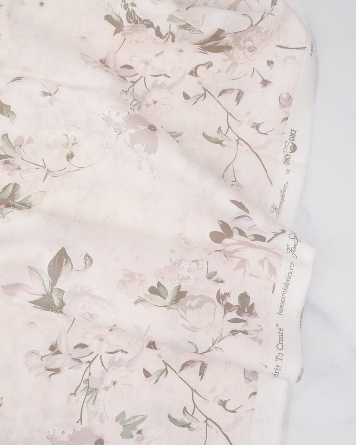 A piece of cotton fabric with a floral pattern in varying shades of gray and white, labeled with the brand Free Spirit Fabrics and the collection name Enrapture.
