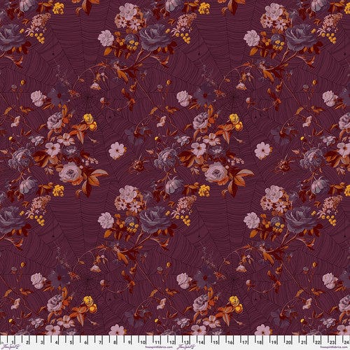 A piece of fabric featuring a floral pattern with shades of purple, pink, and orange on a red background.