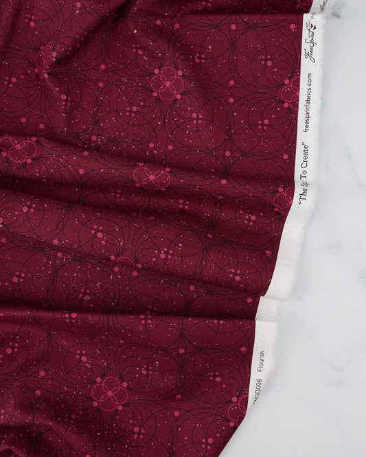 A swatch of 'Flourish in Garnet' fabric from the 'Enrapture' collection by Giucy Giuce for Free Spirit Fabrics, displaying a floral pattern on a garnet red background.
