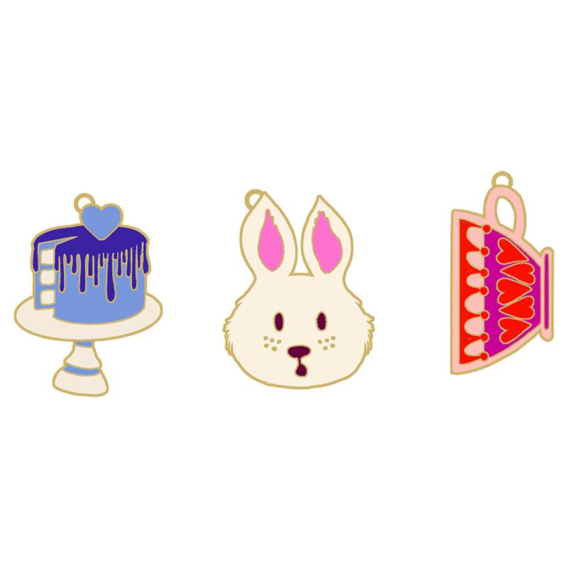 Three enamel zipper pulls; a cake, a rabbit, and a slice of cake on a white background