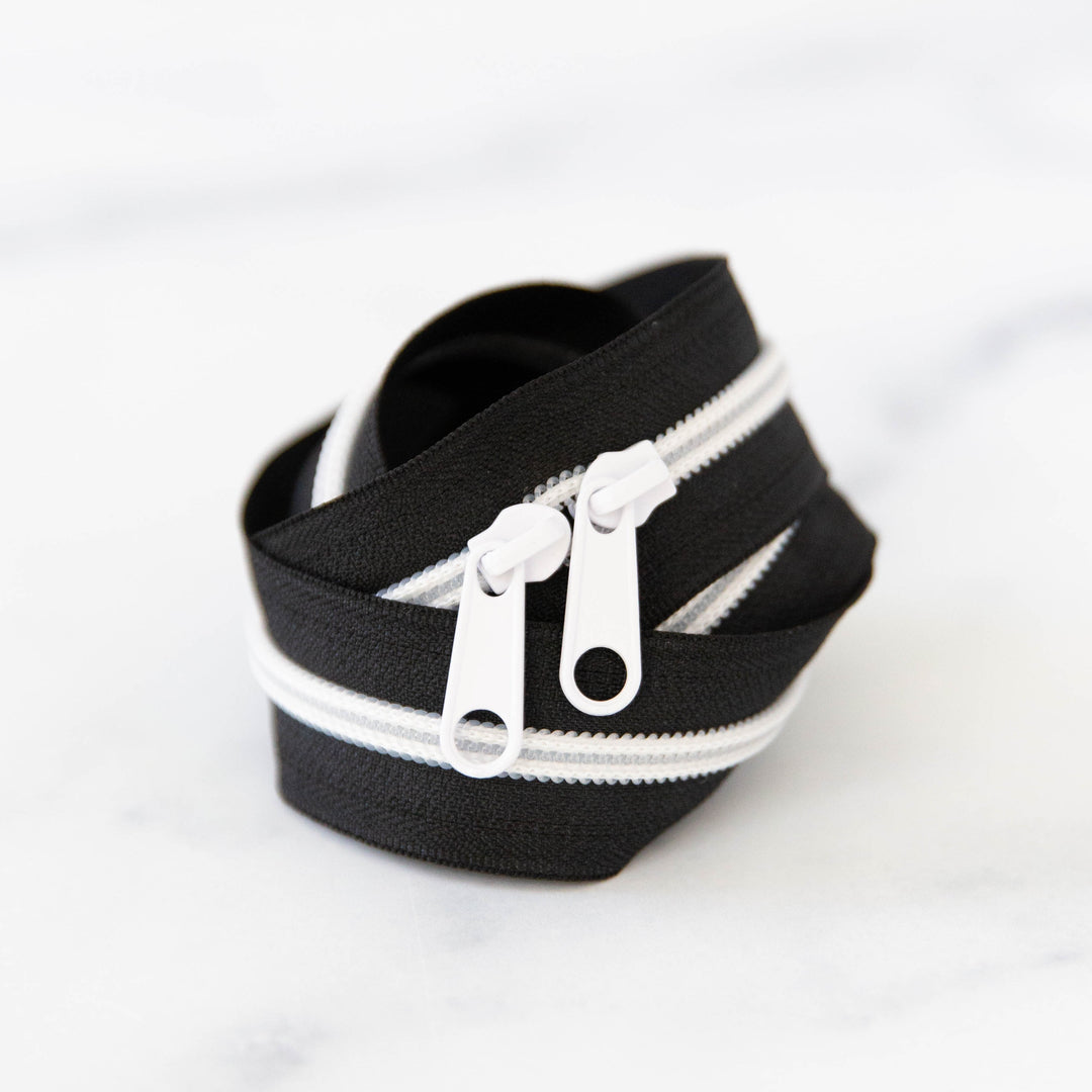 Black zipper with white zipper teeth on a white background
