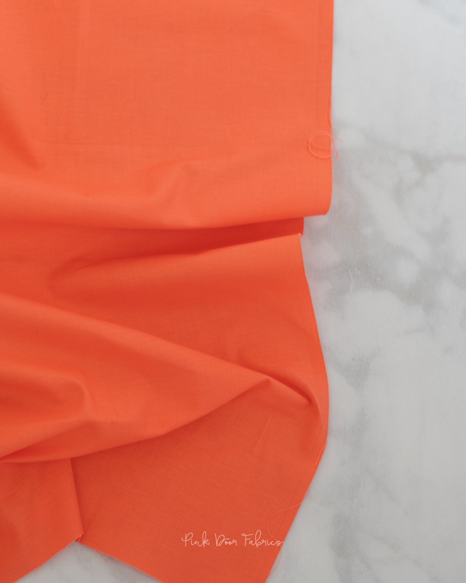 Cotton quilting fabric pattern called 'Solid in Persimmon'. Part of the 'True Colors' fabric collection. Designed by Tula Pink for fabric company Free Spirit Fabrics. SKU: CSFSESS.PERSIMMON. 44-45 inch width.