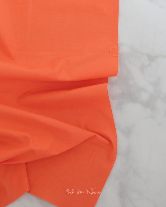 Cotton quilting fabric pattern called 'Solid in Persimmon'. Part of the 'True Colors' fabric collection. Designed by Tula Pink for fabric company Free Spirit Fabrics. SKU: CSFSESS.PERSIMMON. 44-45 inch width.