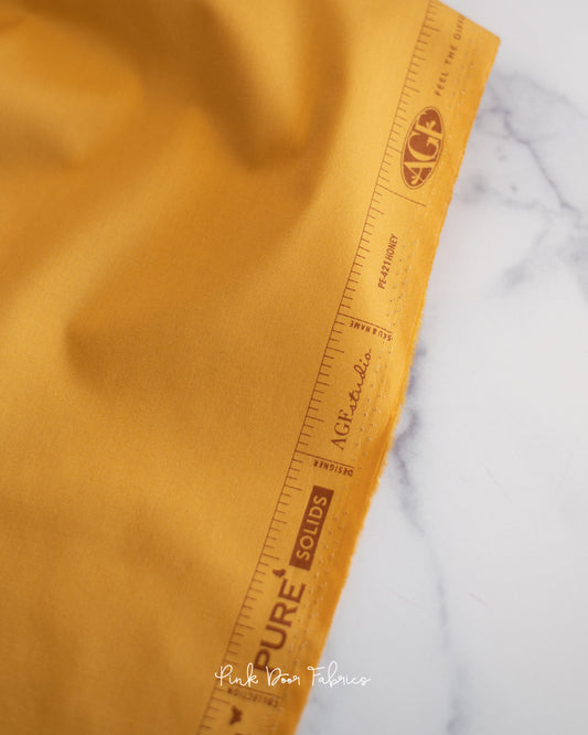 Cotton quilting fabric pattern called 'Honey'. Part of the 'Pure Solids' fabric collection. Designed by Art Gallery Fabrics for fabric company Art Gallery Fabrics. SKU: PE-421. 44-45 inch width.