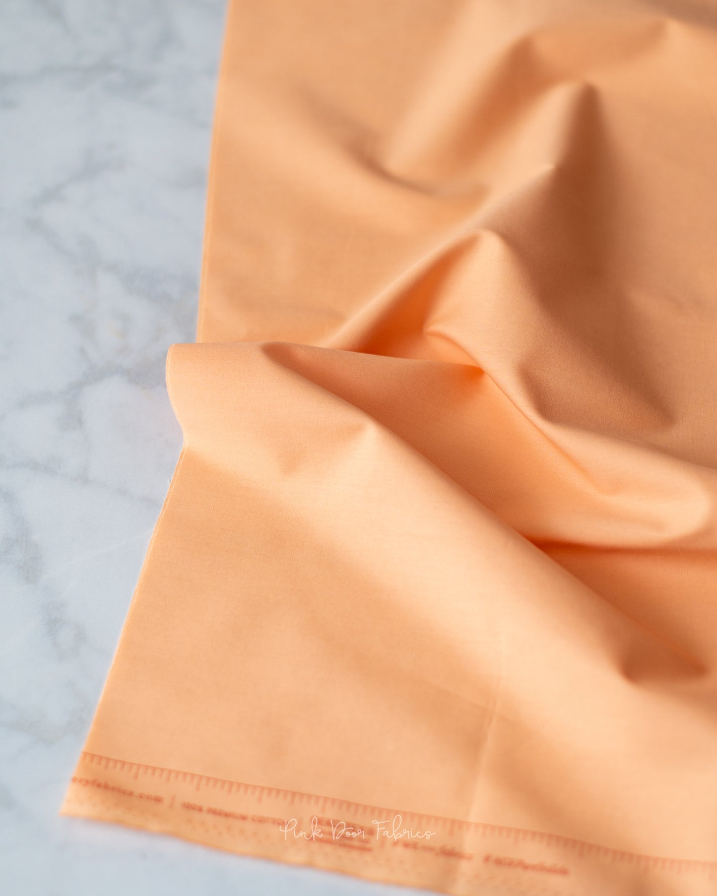 Cotton quilting fabric pattern called 'Georgia Peach'. Part of the 'Pure Solids' fabric collection. Designed by Art Gallery Fabrics for fabric company Art Gallery Fabrics. SKU: PE-509. 44-45 inch width.