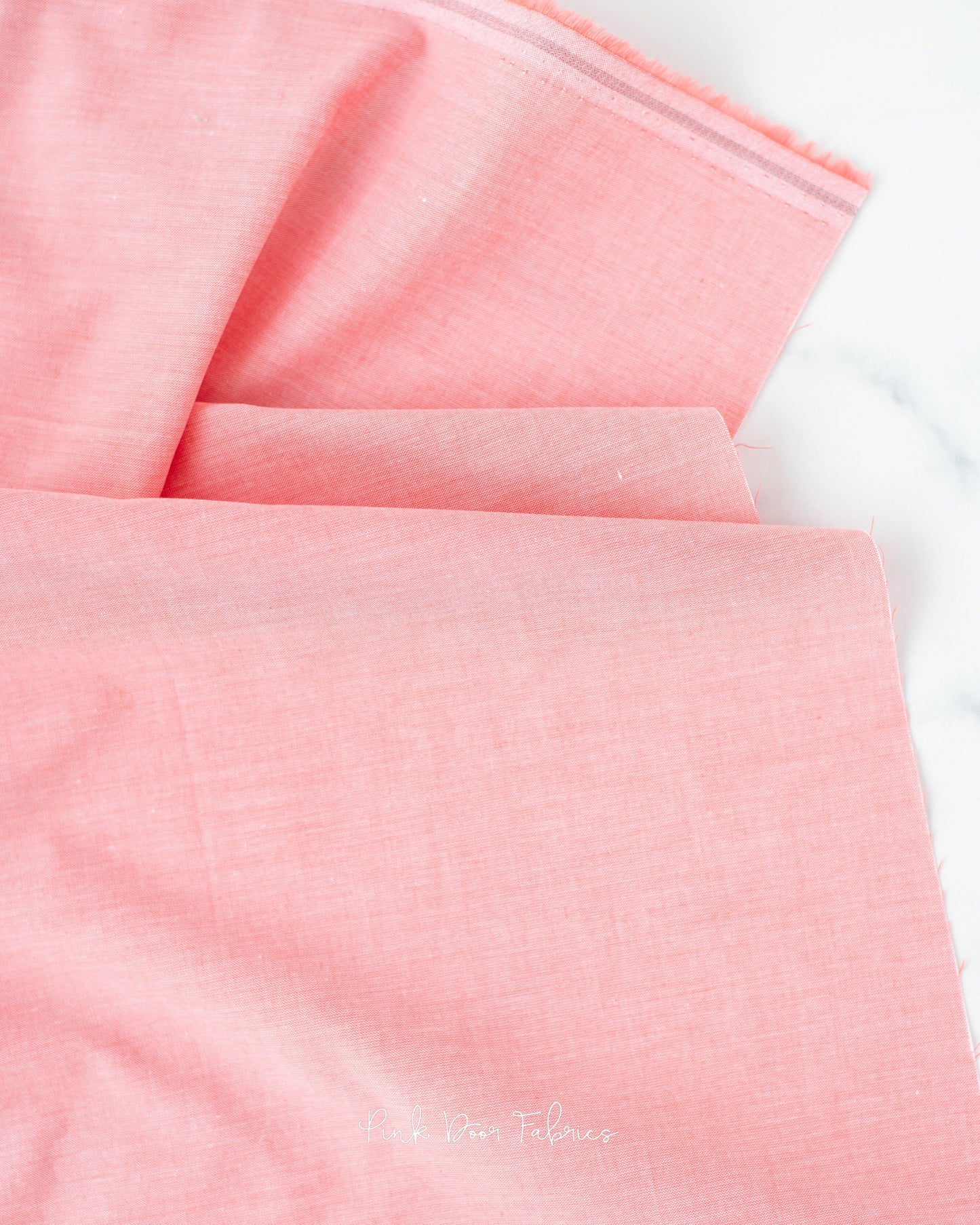 Chambray quilting fabric pattern called 'Coral'. Part of the 'Chambray Solids' fabric collection. Designed by Tilda Fabrics for the Tilda Fabrics fabric company. SKU: 160014. 44-45 inch width.