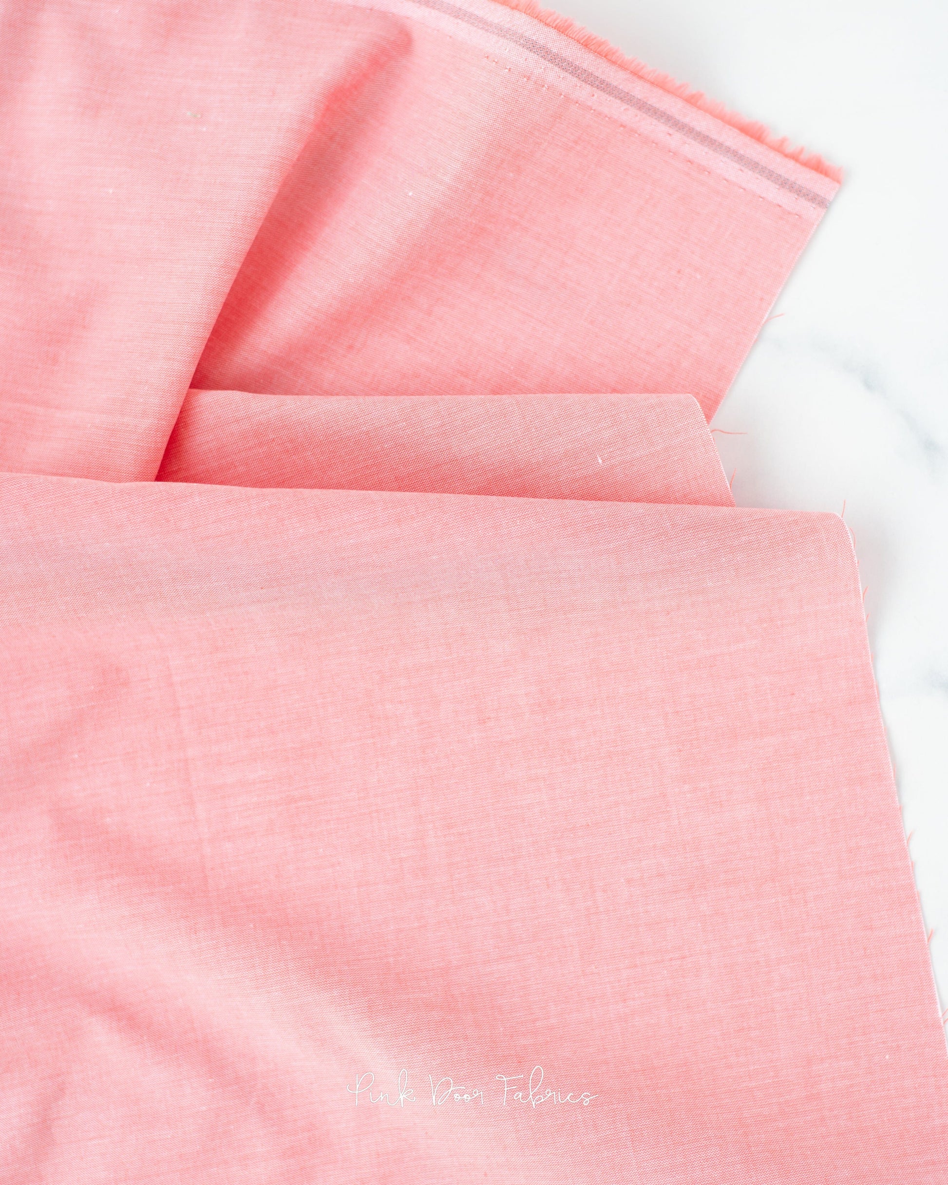 Chambray quilting fabric pattern called 'Coral'. Part of the 'Chambray Solids' fabric collection. Designed by Tilda Fabrics for the Tilda Fabrics fabric company. SKU: 160014. 44-45 inch width.