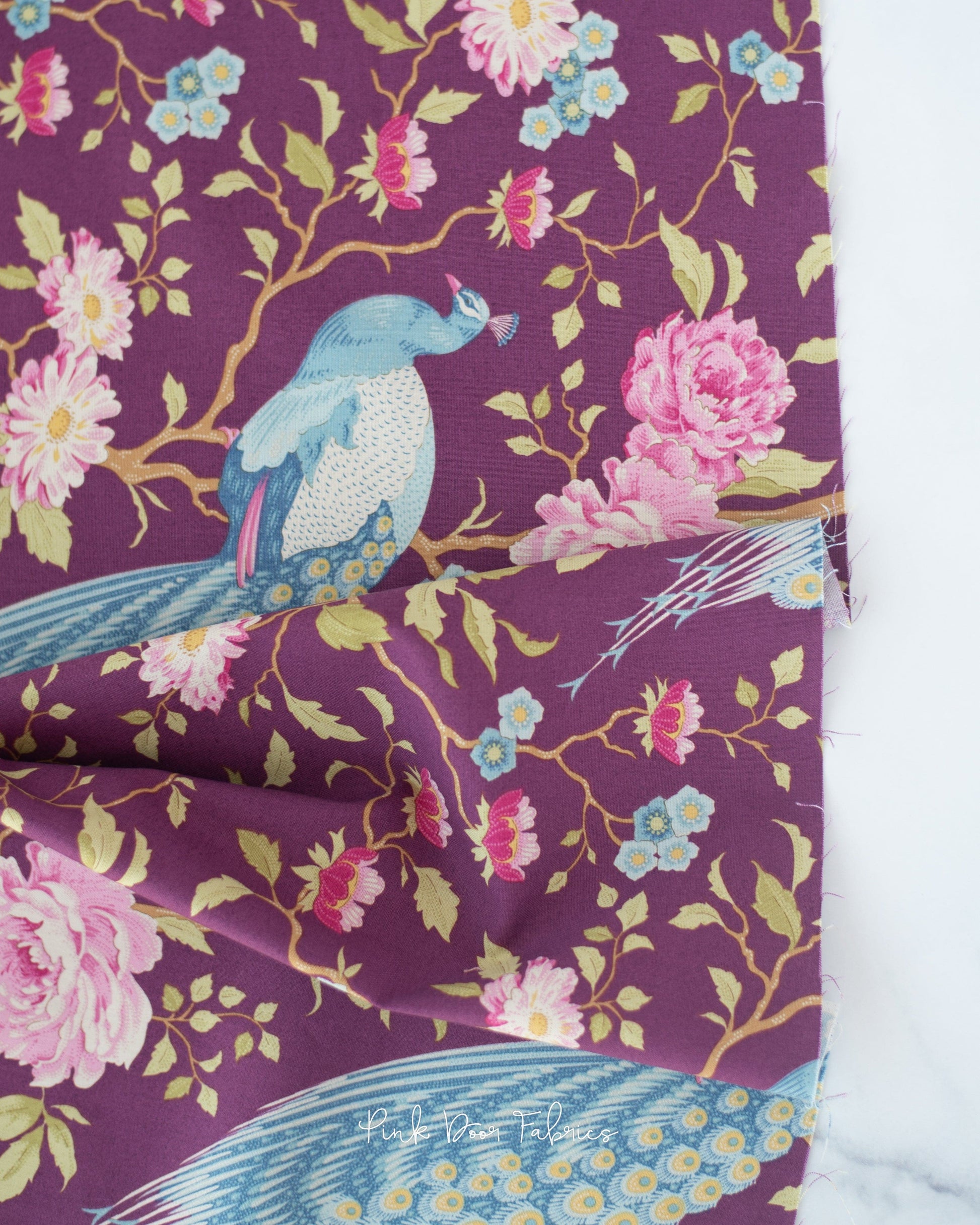 Cotton quilting fabric pattern called 'Peacock Tree in Grape'. Part of the 'Chic Escape' fabric collection. Designed by Tilda Fabrics for fabric company Tilda Fabrics. SKU: 100457. 44-45 inch width.